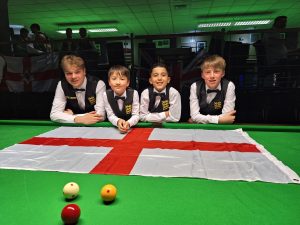 Junior players pose in waistcoats at the table behind an England flag.