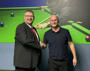 Tournament director James Chambers shakes hands with Craig Steadman. Both are smiling.